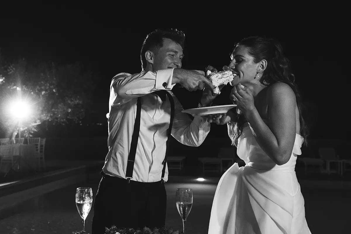 Groom plays with bride and wedding cake
