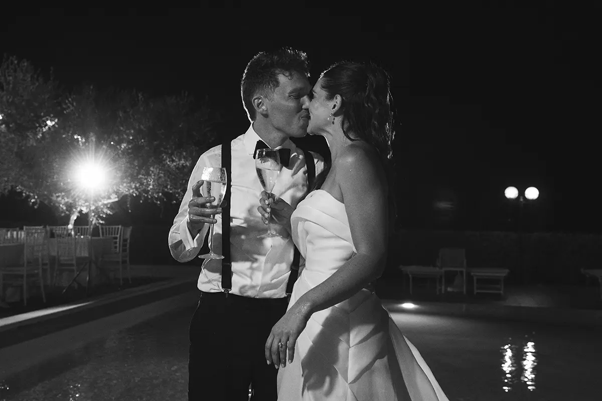 Newlyweds kiss with glasses of champagne in their hands