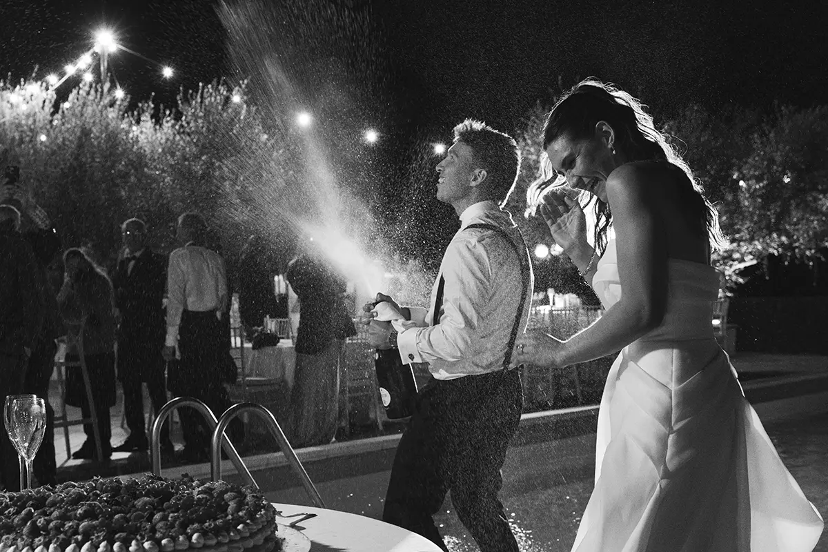 Groom splashes champagne as bride smiles