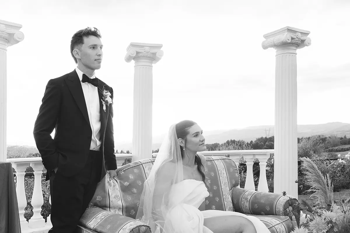 Newlyweds sitting on a sofa in front of a colonnade