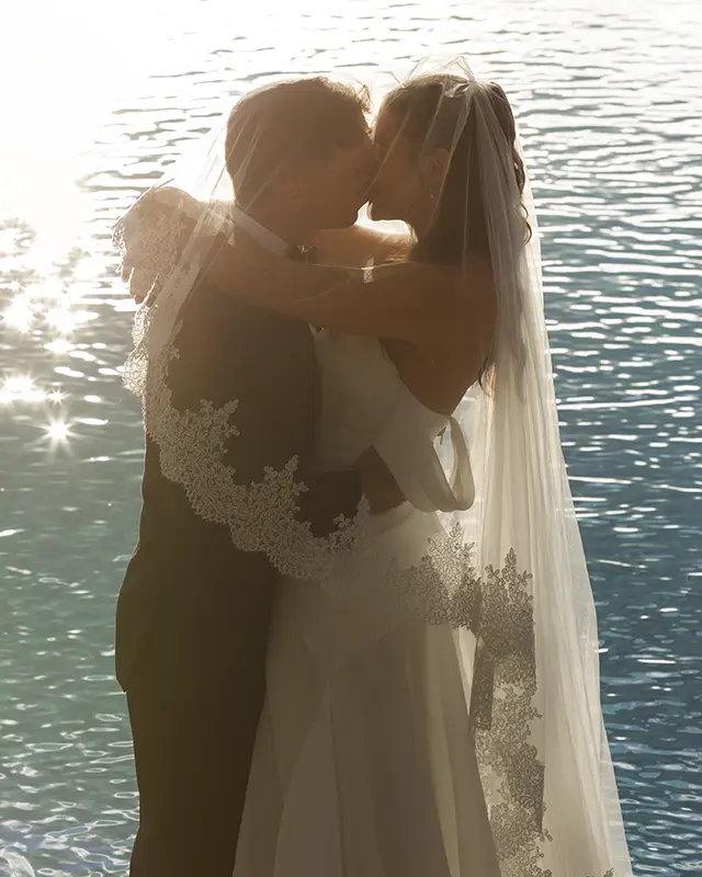 Newlyweds kiss at sunset in front of the pool