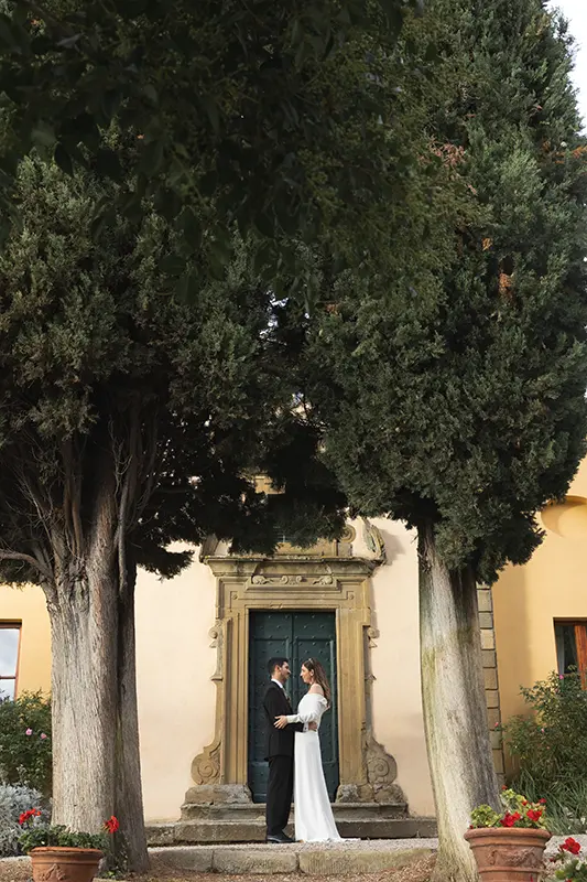 Newlyweds embrace in front of the old church of the Relais il Falconiere
