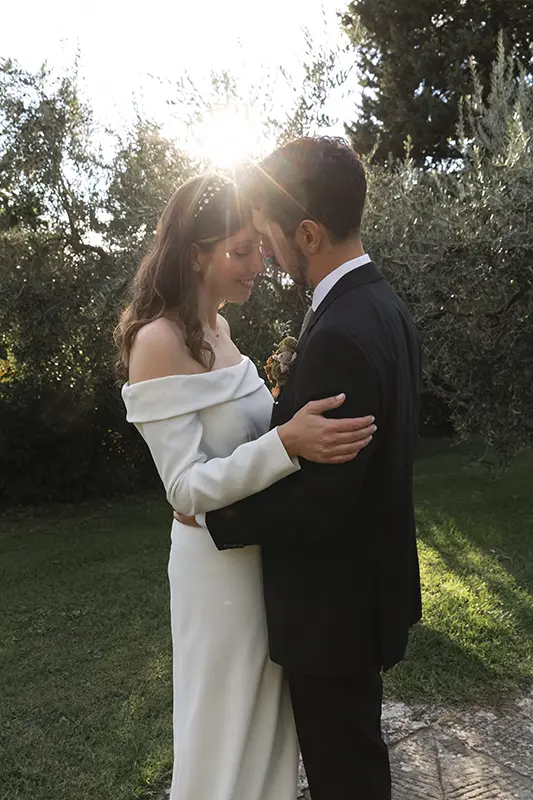 Newlyweds embrace with the sun behind them
