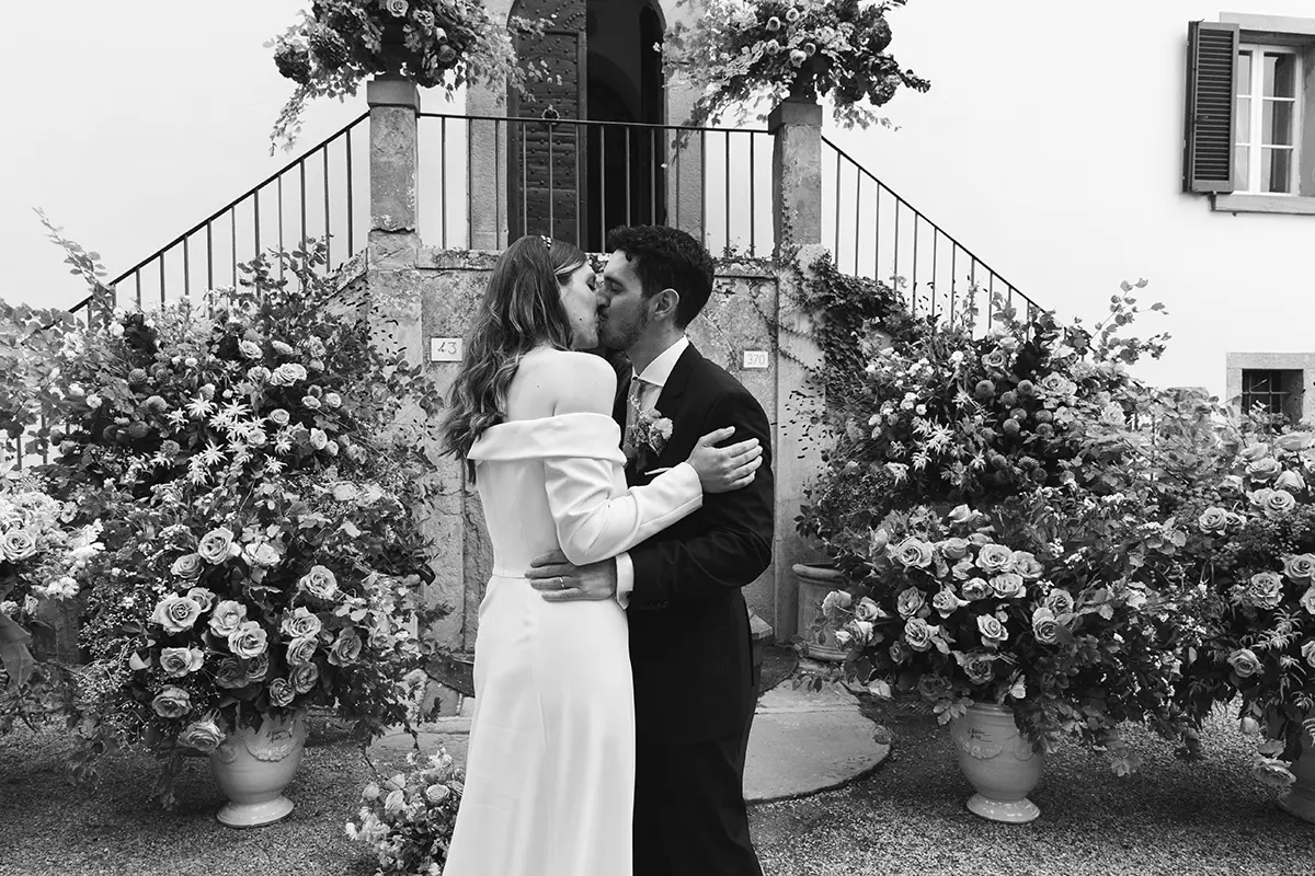 Newlyweds kiss in front of many flowers