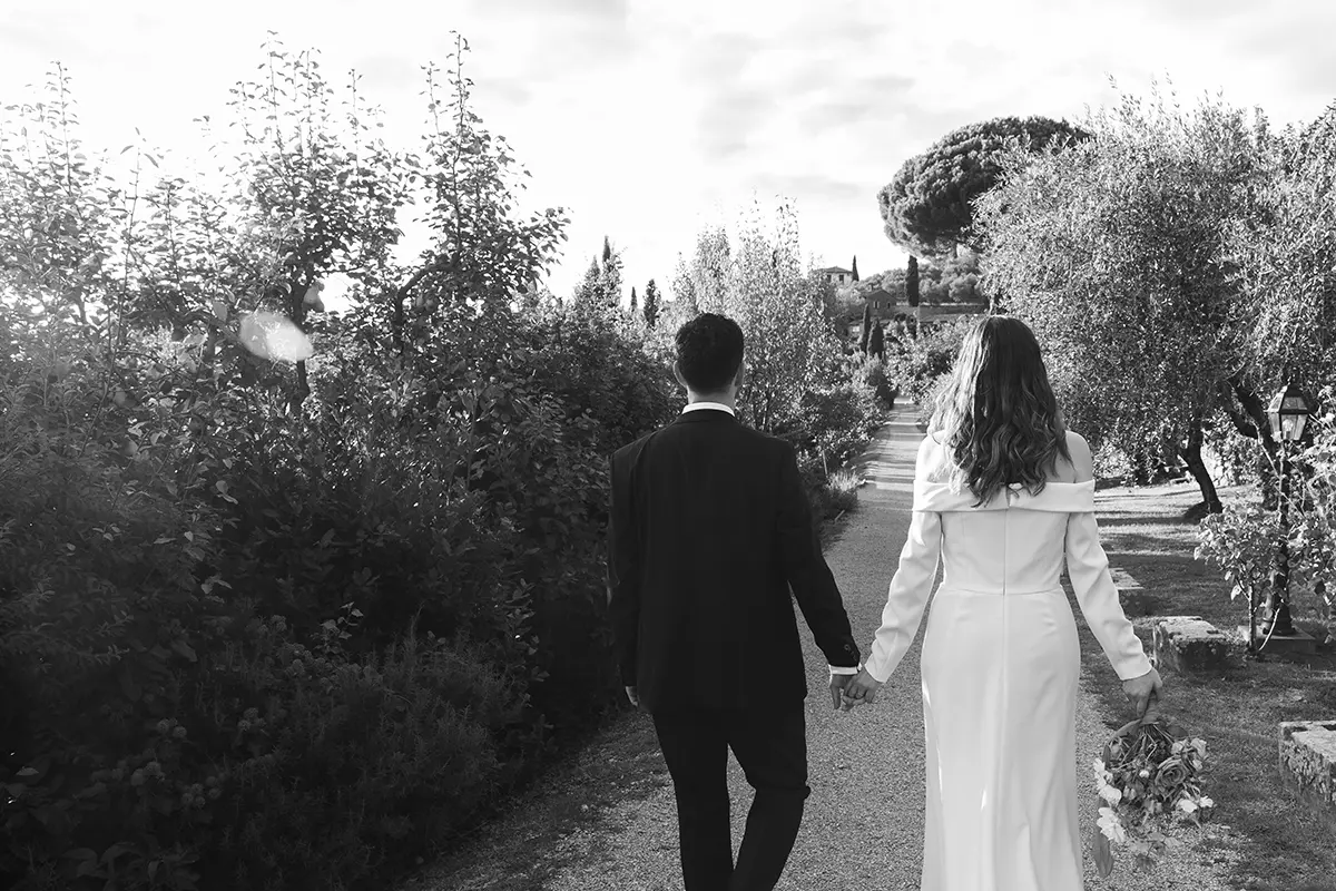 Newlyweds stroll along an avenue inside a Tuscan villa