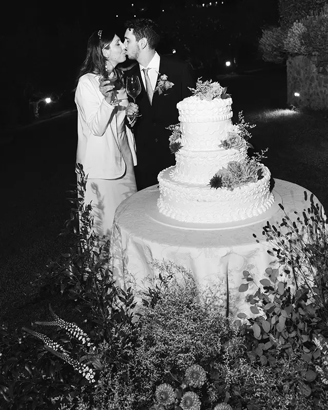 Newlyweds kiss behind the wedding cake