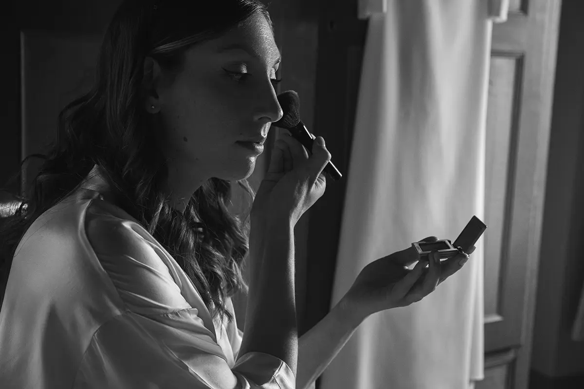 Bride puts on makeup in front of her dress