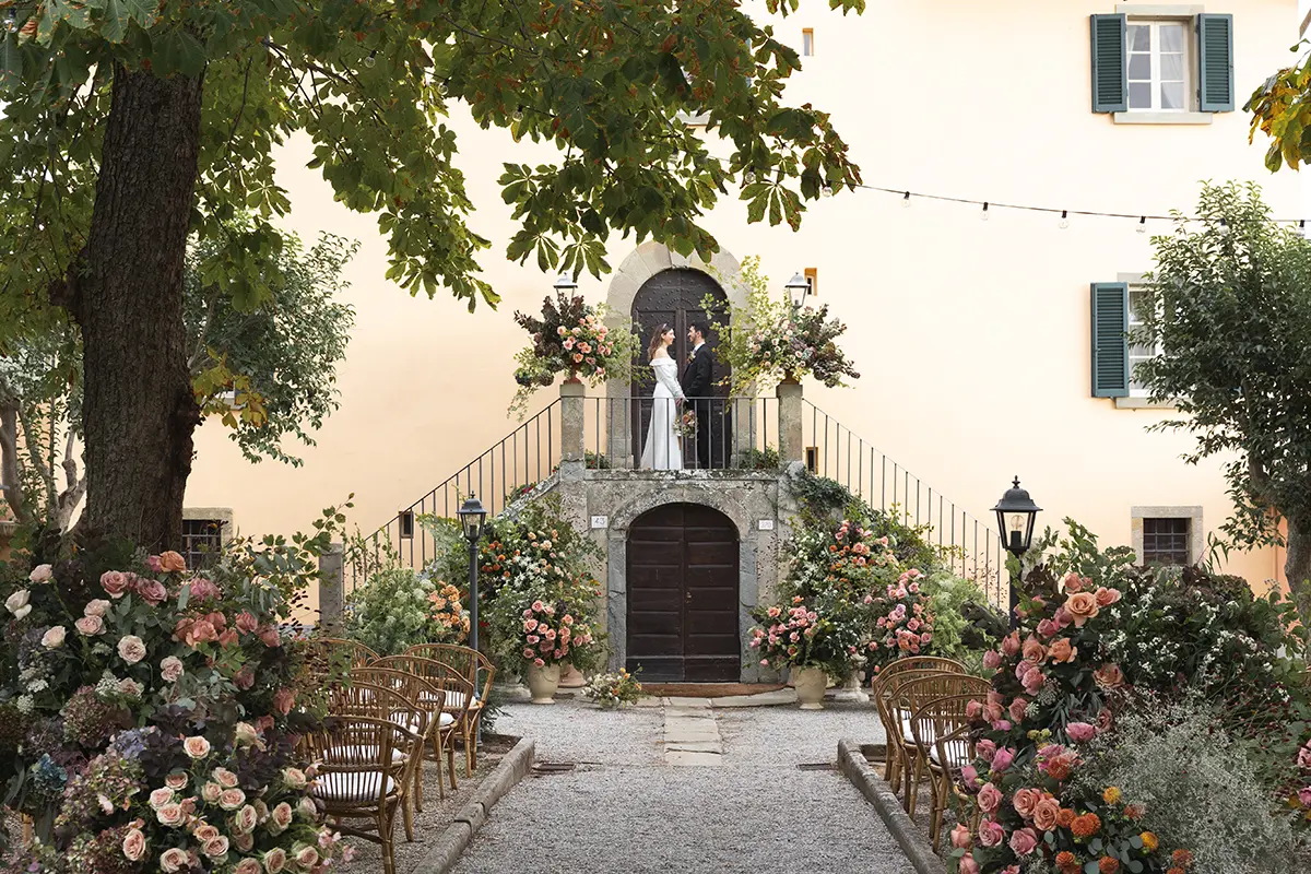 Bride and groom in an italian villa with many autumn-colored flowers